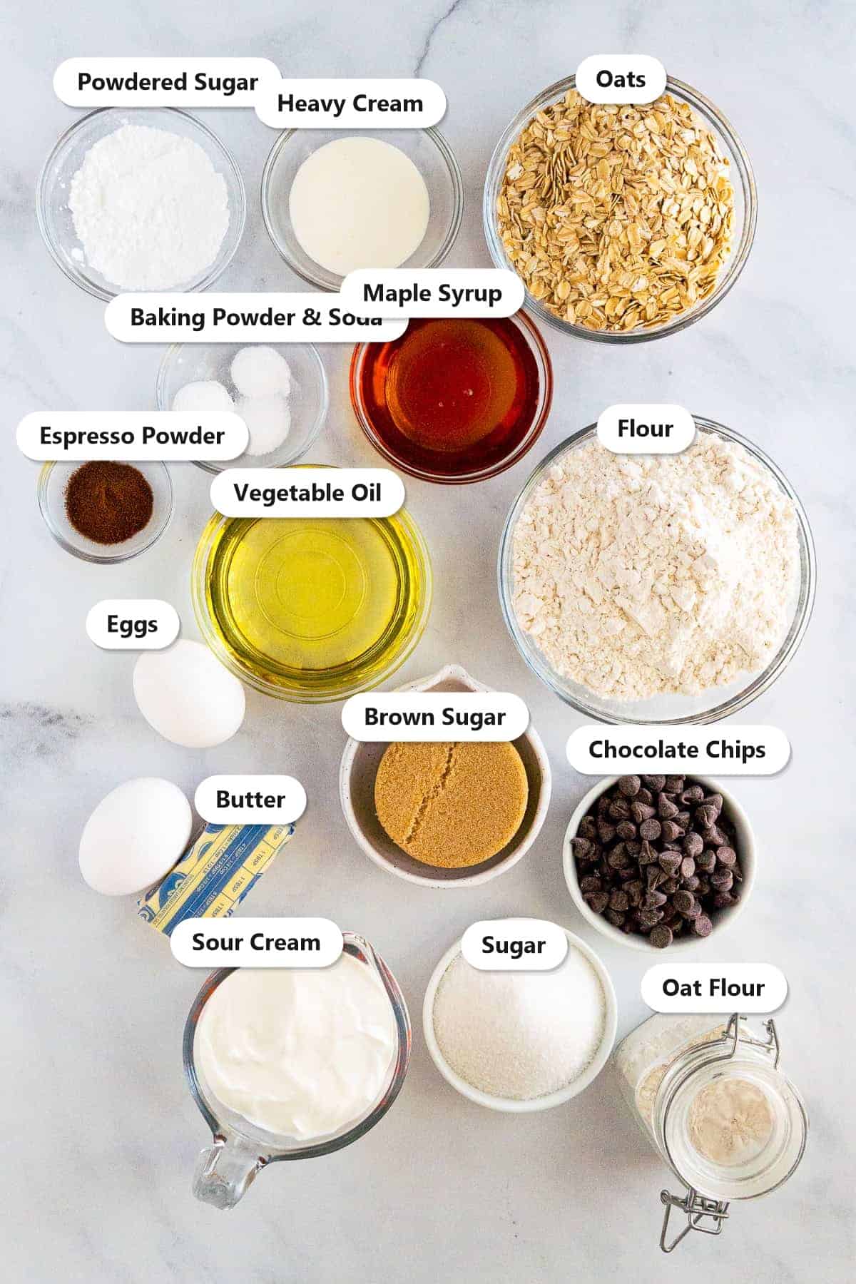 Labeled ingredients for chocolate chip oatmeal muffins including oats, flour, sour cream, maple syrup, brown sugar, and chocolate chips.