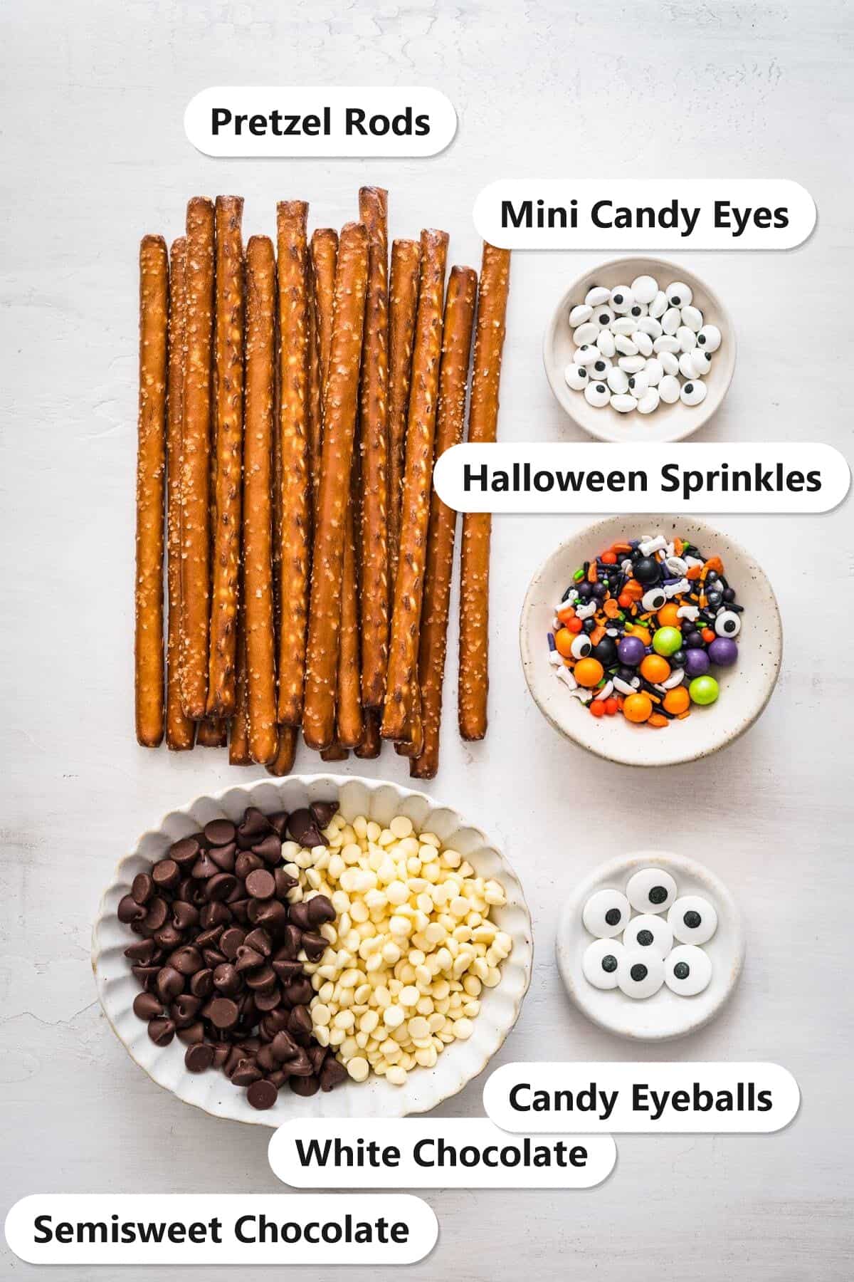 Labeled ingredients for Chocolate Covered Pretzel Rods: pretzel rods, semisweet chocolate, white chocolate, Halloween sprinkles, mini candy eyes, and candy eyeballs.