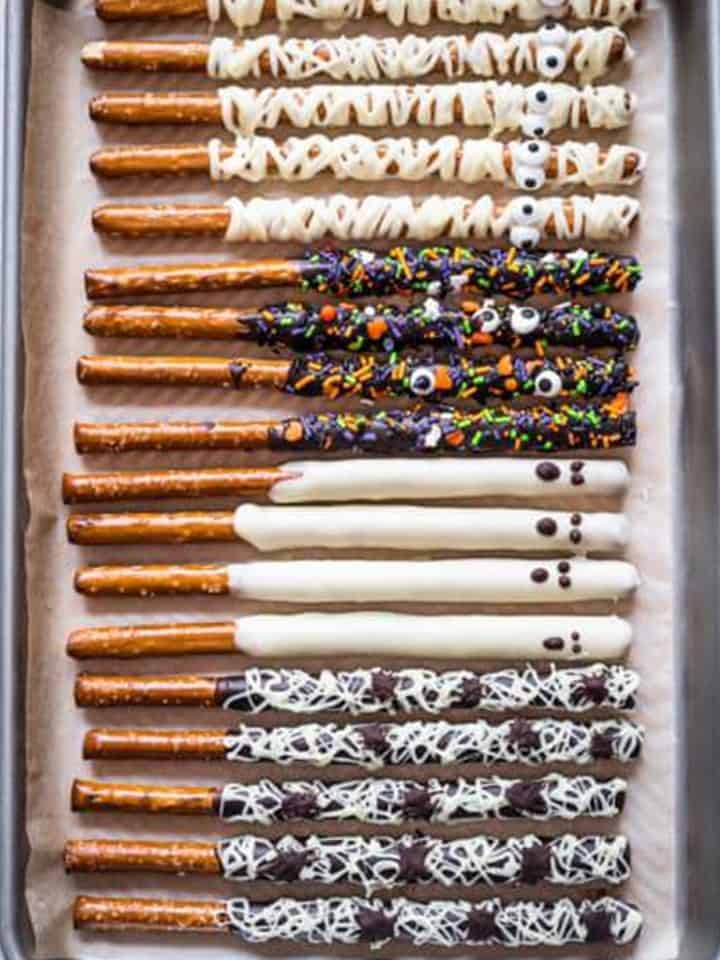 Finished chocolate covered pretzel rods in every style setting on a parchment lined tray.