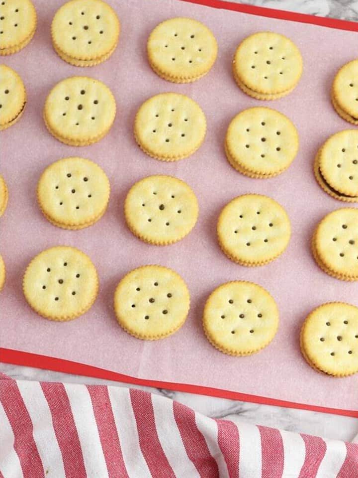Ritz crackers sandwiched together over the mint frosting filling on a lined tray.