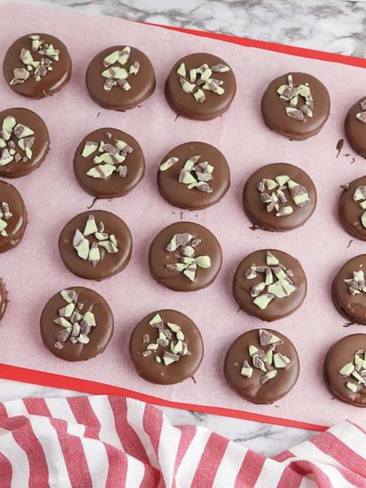 Chocolate covered Ritz crackers topped with chopped Andes mints setting on parchment paper.