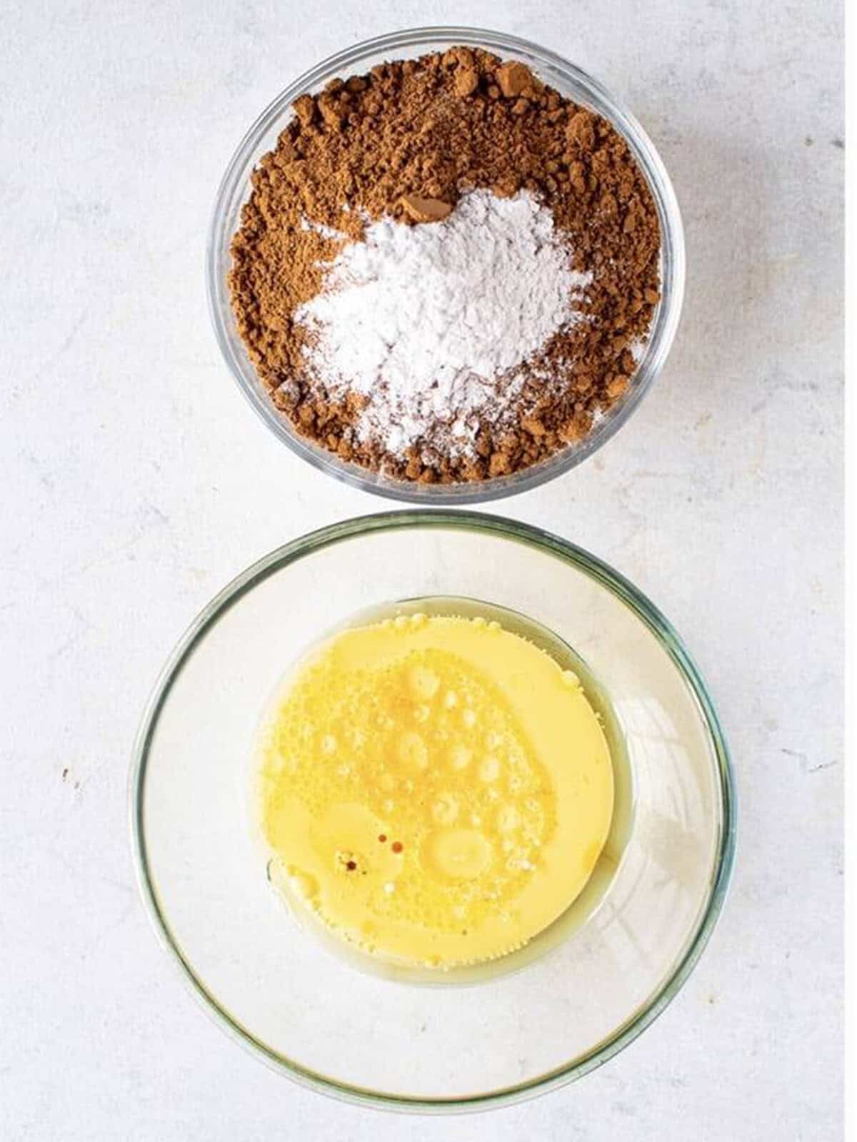 Dry ingredients whisked in one bowl and wet ingredients mixed in another for chocolate cupcakes.