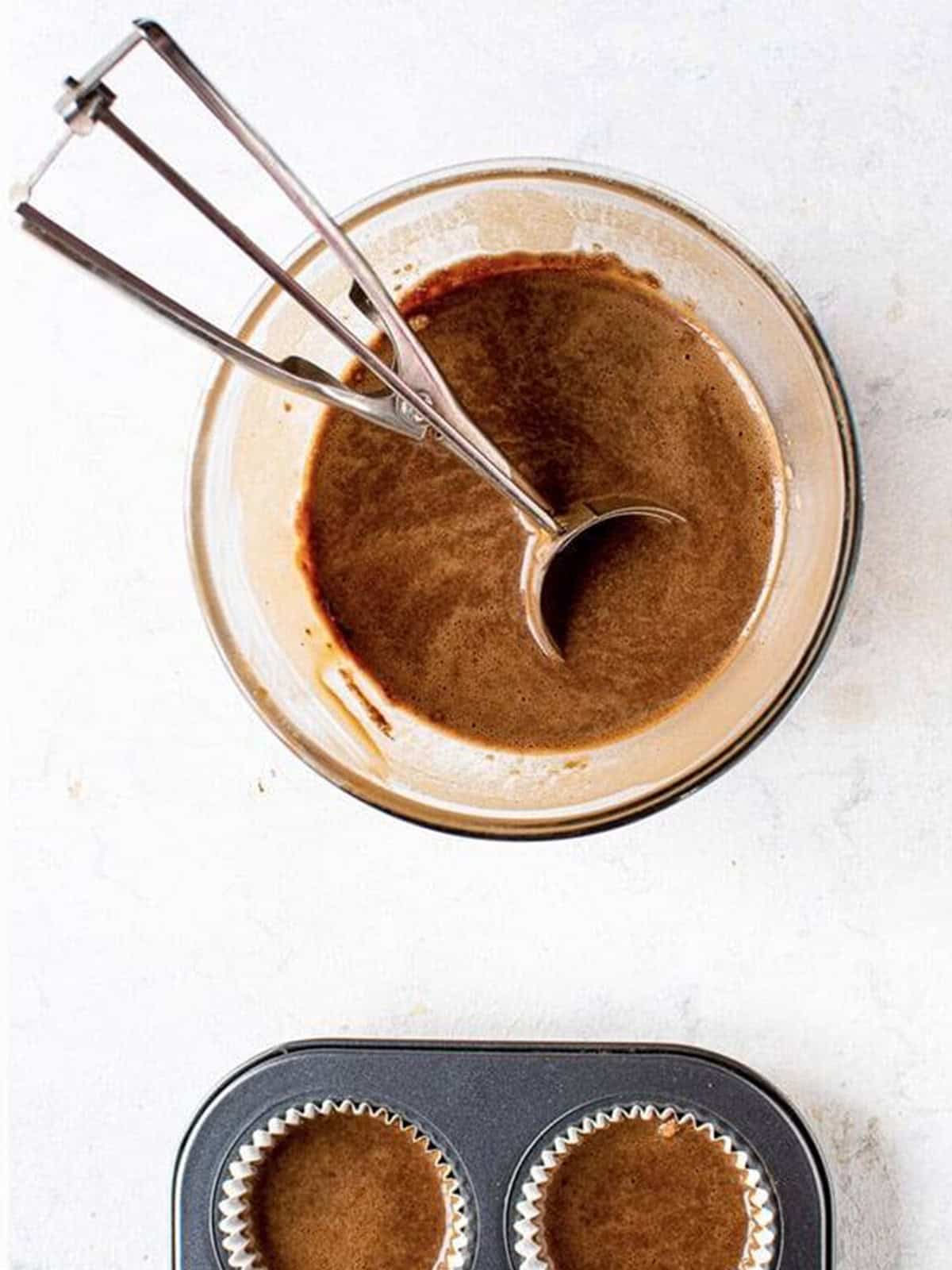 Chocolate cupcake batter scooped into lined cupcake pans ready to bake.