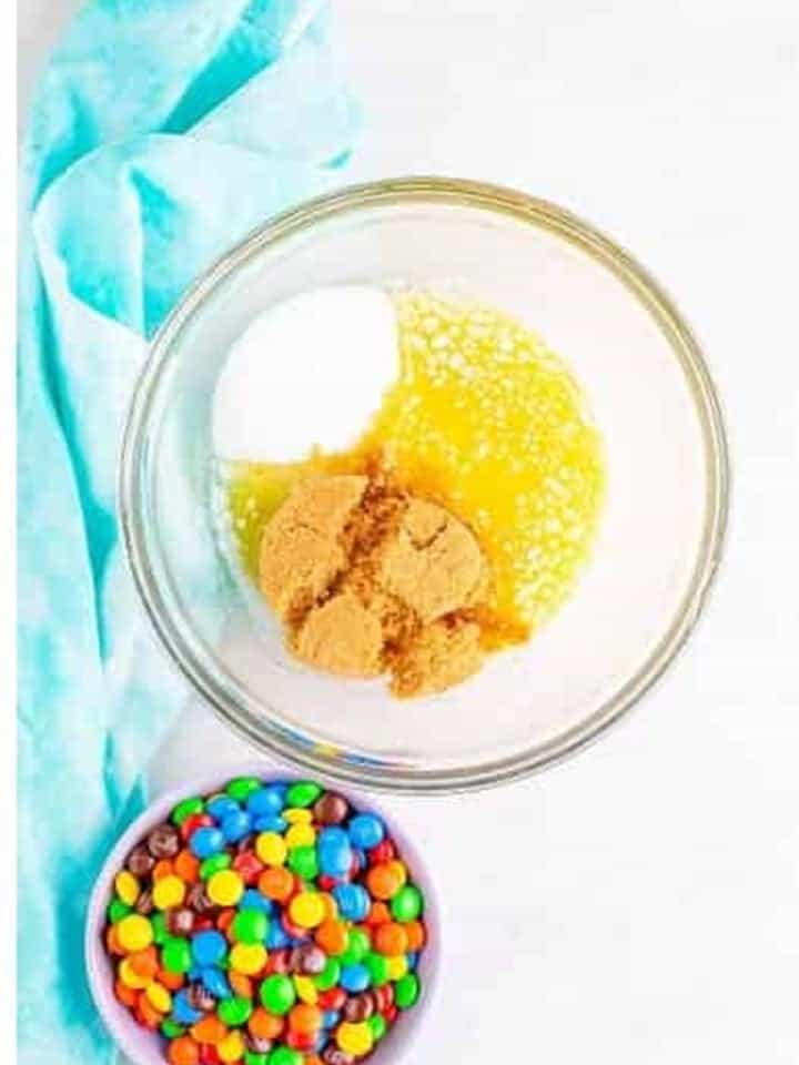 Melted butter, brown sugar, and granulated sugar in a glass bowl for chocolate m&m cookies.