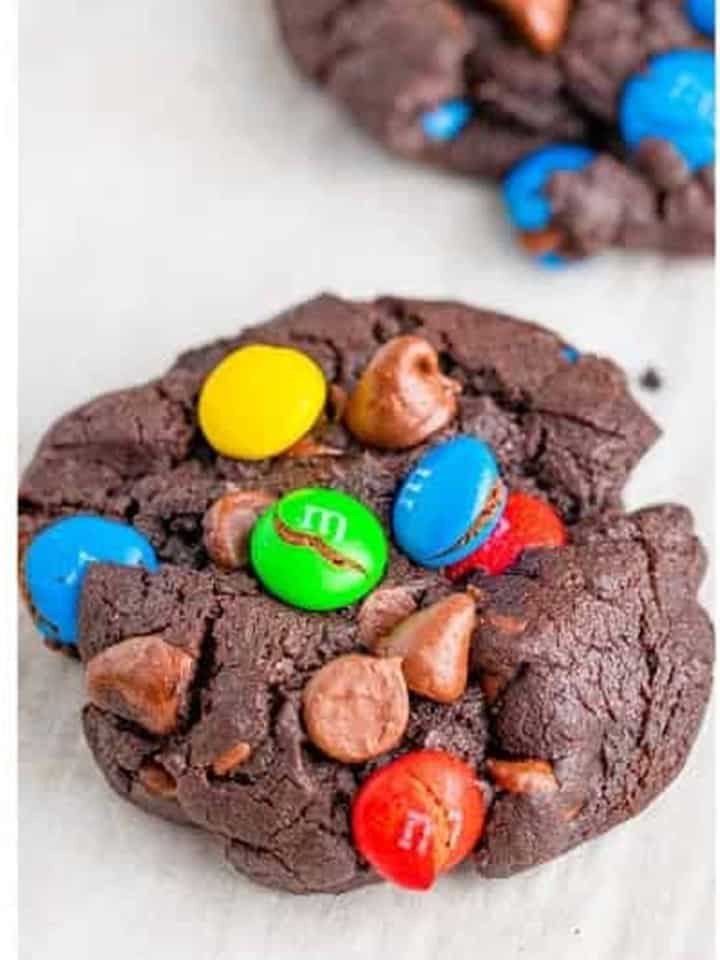 A baked chocolate m&m cookie showing the melty chips and colorful candies on top.