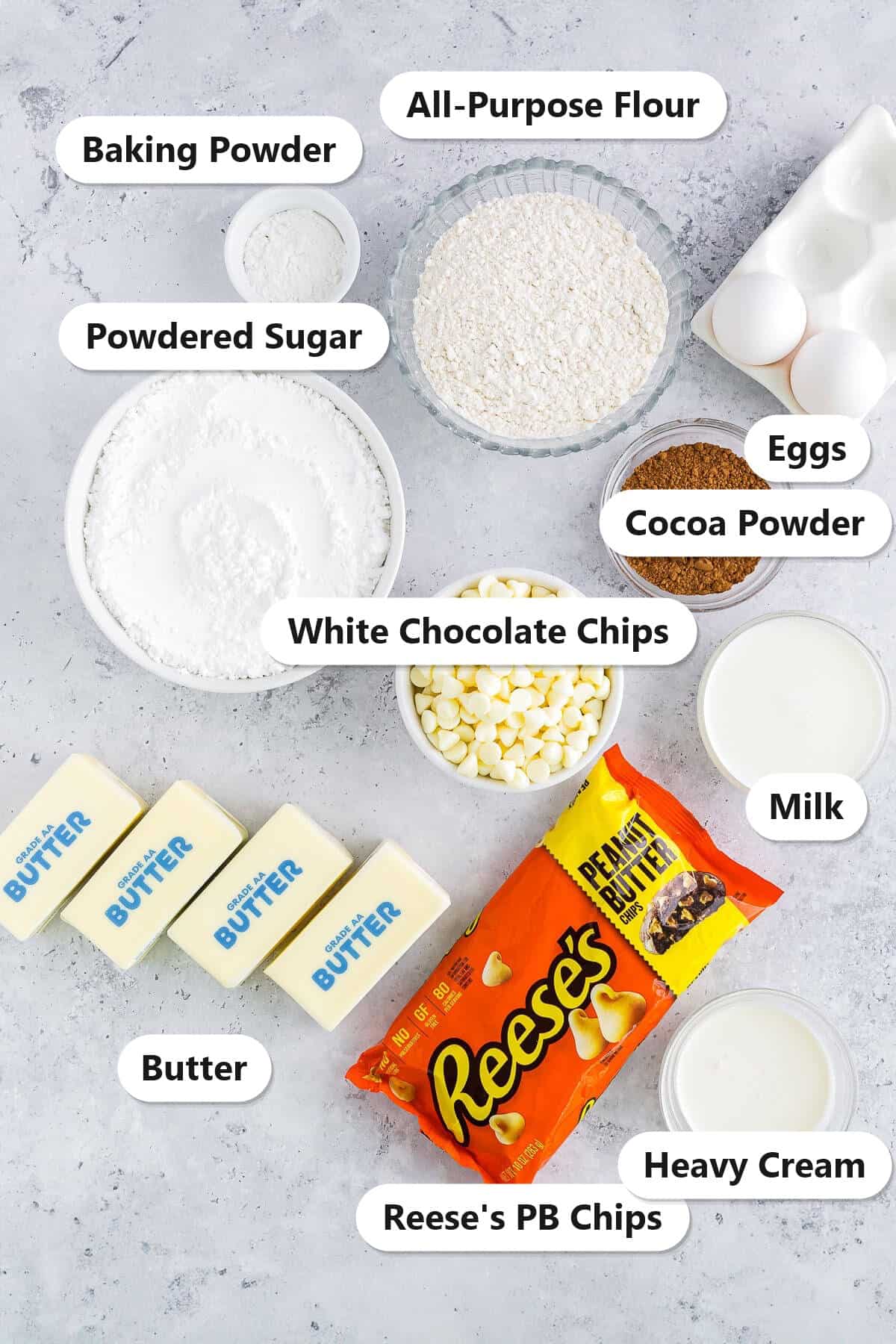 Labeled ingredients for chocolate peanut butter cupcakes including flour, cocoa powder, butter, Reeses peanut butter chips, white chocolate chips, and heavy cream.