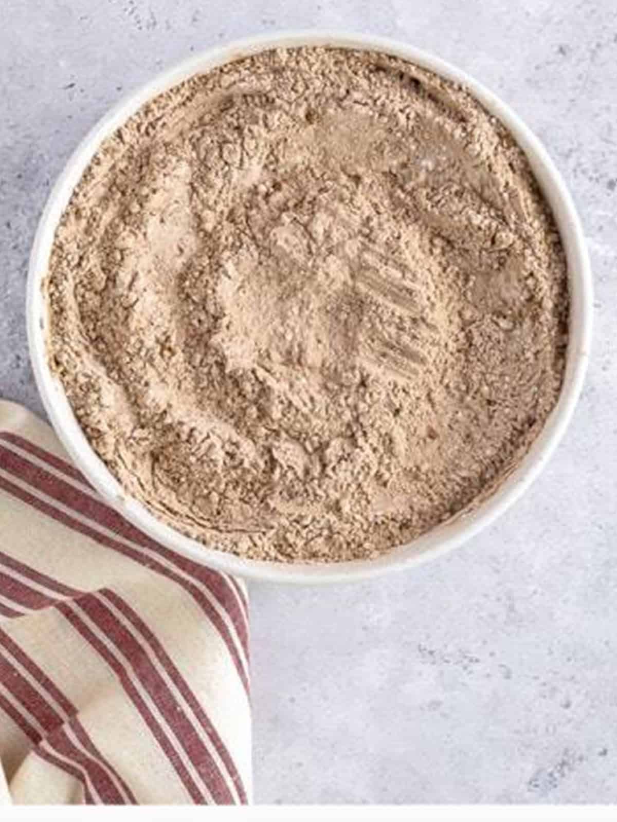 Flour, sugar, cocoa powder, and baking powder mixed in a white bowl.