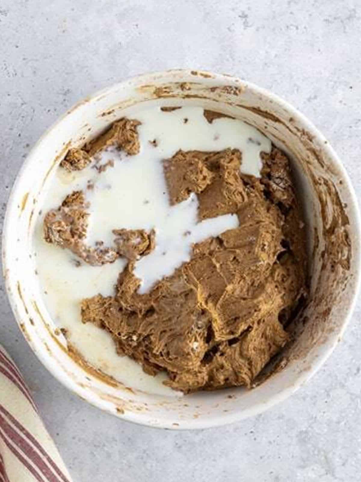 Milk added to the chocolate cupcake batter in a mixing bowl.