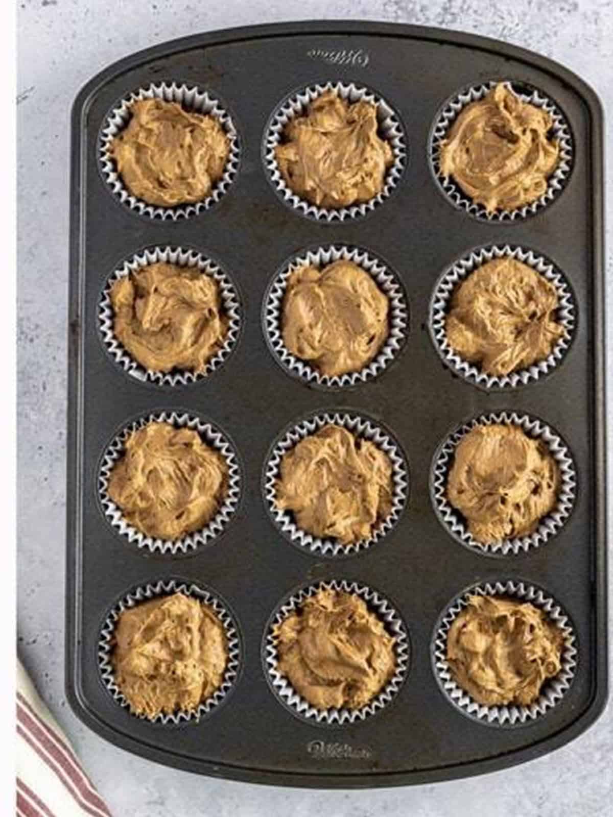 Chocolate peanut butter cupcake batter divided between lined cupcake wells.