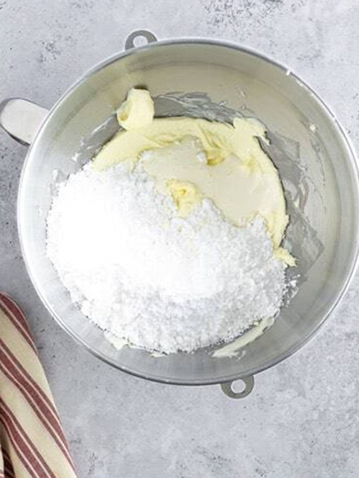Powdered sugar added to creamed butter for the white chocolate frosting.