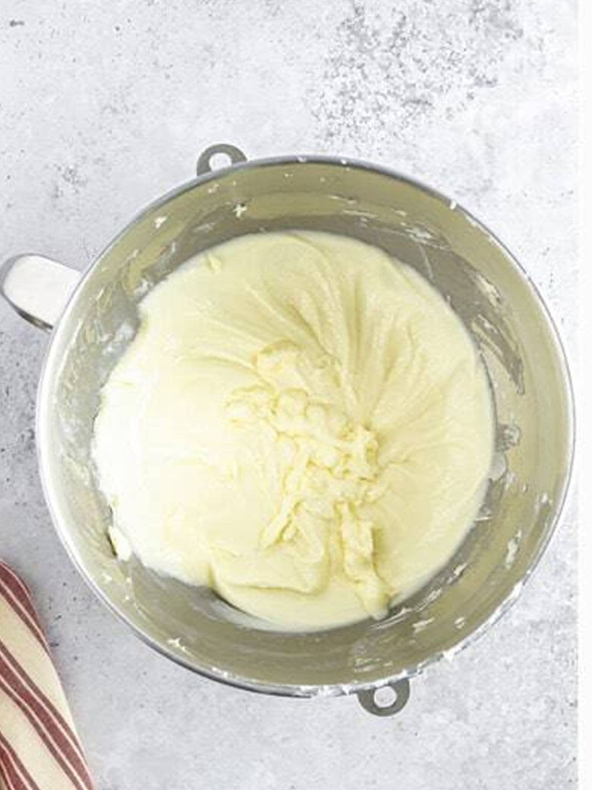 Whipped white chocolate frosting in a stand mixer bowl.