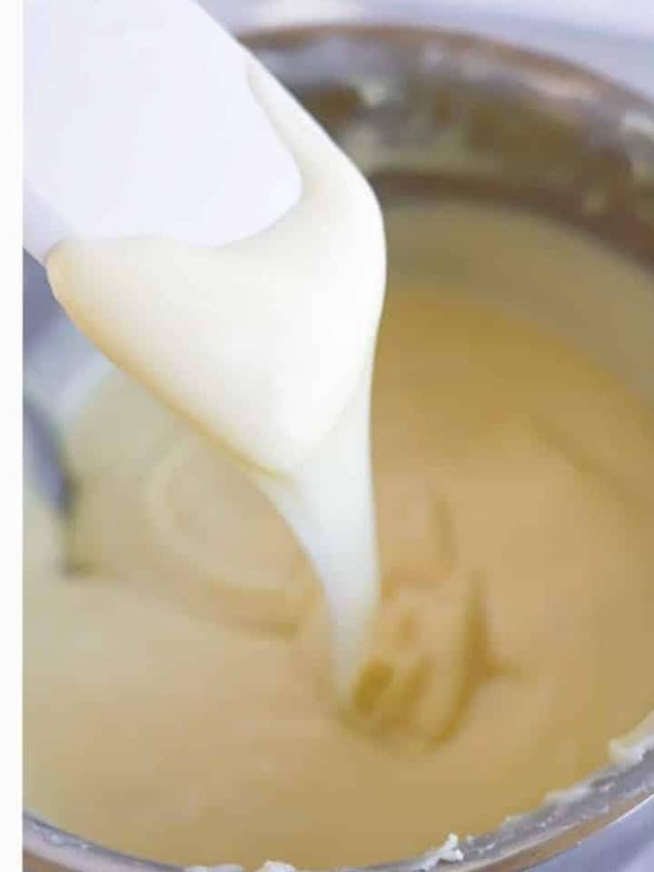 Melted white fudge base being stirred smooth with a spatula for christmas fudge.