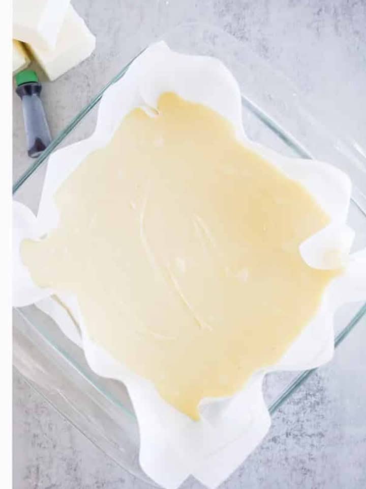 White christmas fudge poured into a parchment lined square pan to set.