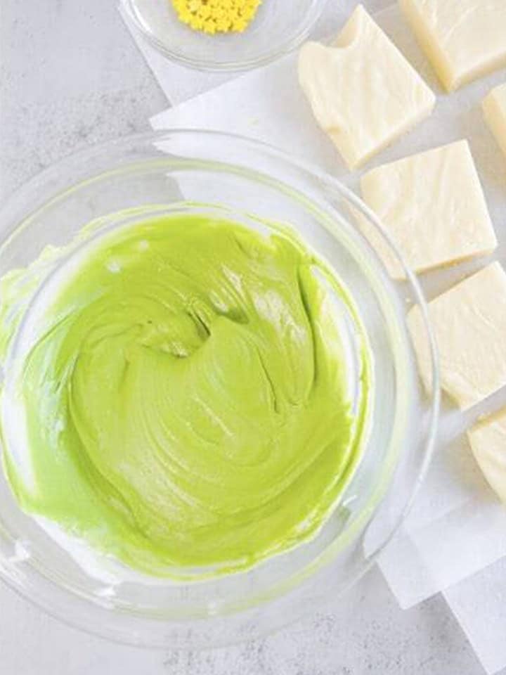 Almond bark stirred to a bright green shade in a glass bowl for decorating christmas fudge.