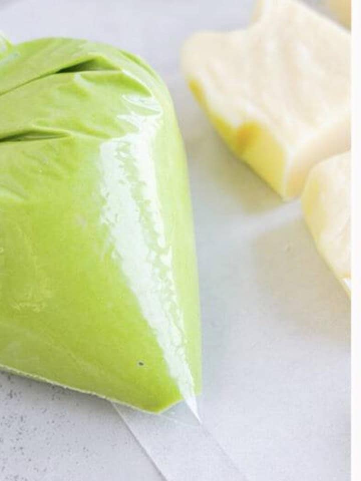Green almond bark in a zippered piping bag with the tip snipped for decorating christmas fudge.