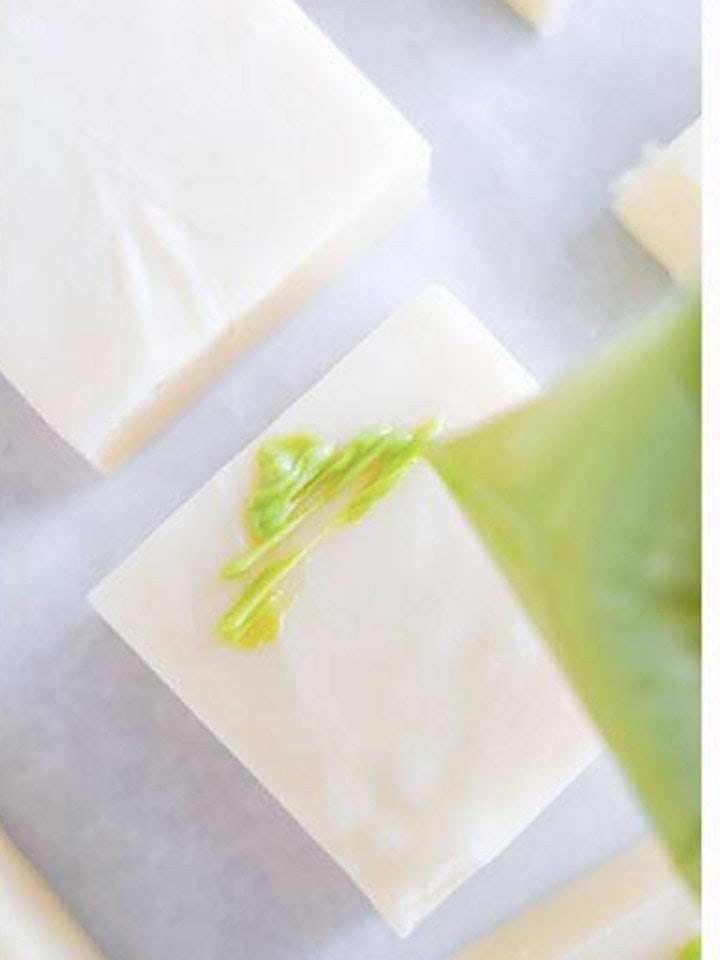 Green tree shape being drizzled onto a square of christmas fudge.