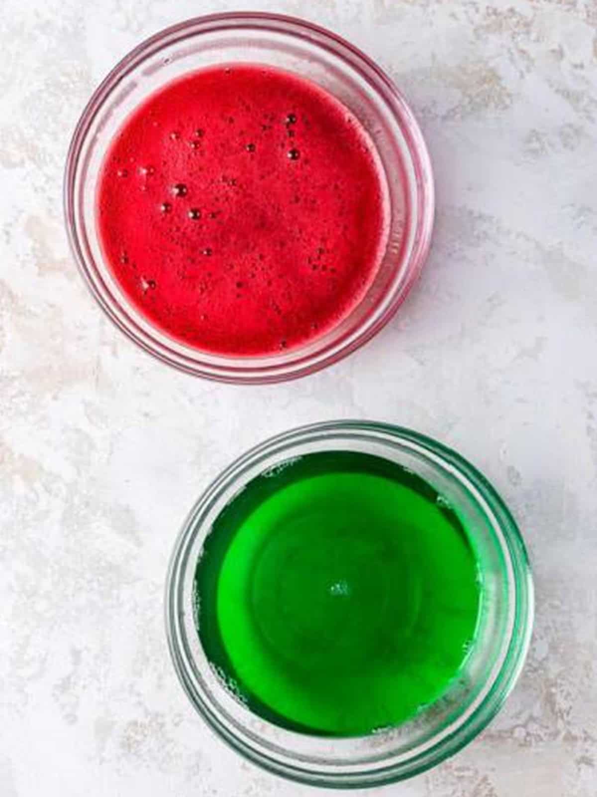 Cherry and lime jello dissolved in separate bowls for Christmas jello salad.