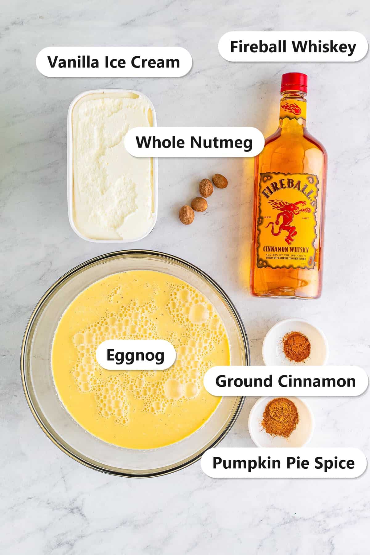 Labeled ingredients for Christmas punch: eggnog, Fireball whiskey, vanilla ice cream, pumpkin pie spice, ground cinnamon, and whole nutmeg.