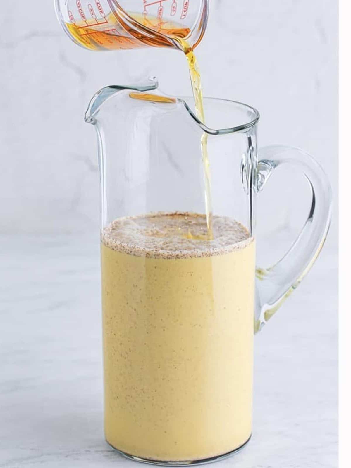 Pouring the mixed Christmas punch from the bowl into a glass pitcher.