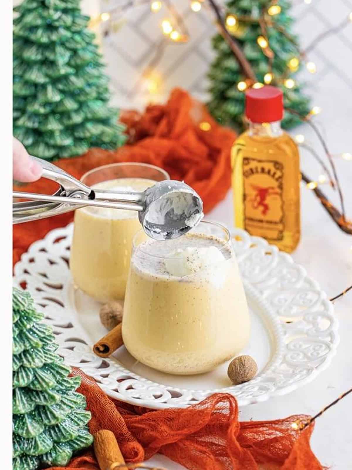 Adding a small scoop of vanilla ice cream on top of a glass of Christmas punch.