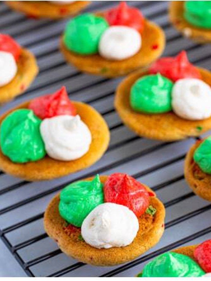 Dollops of red, green, and white frosting piped onto the bottoms of the baked cookies.