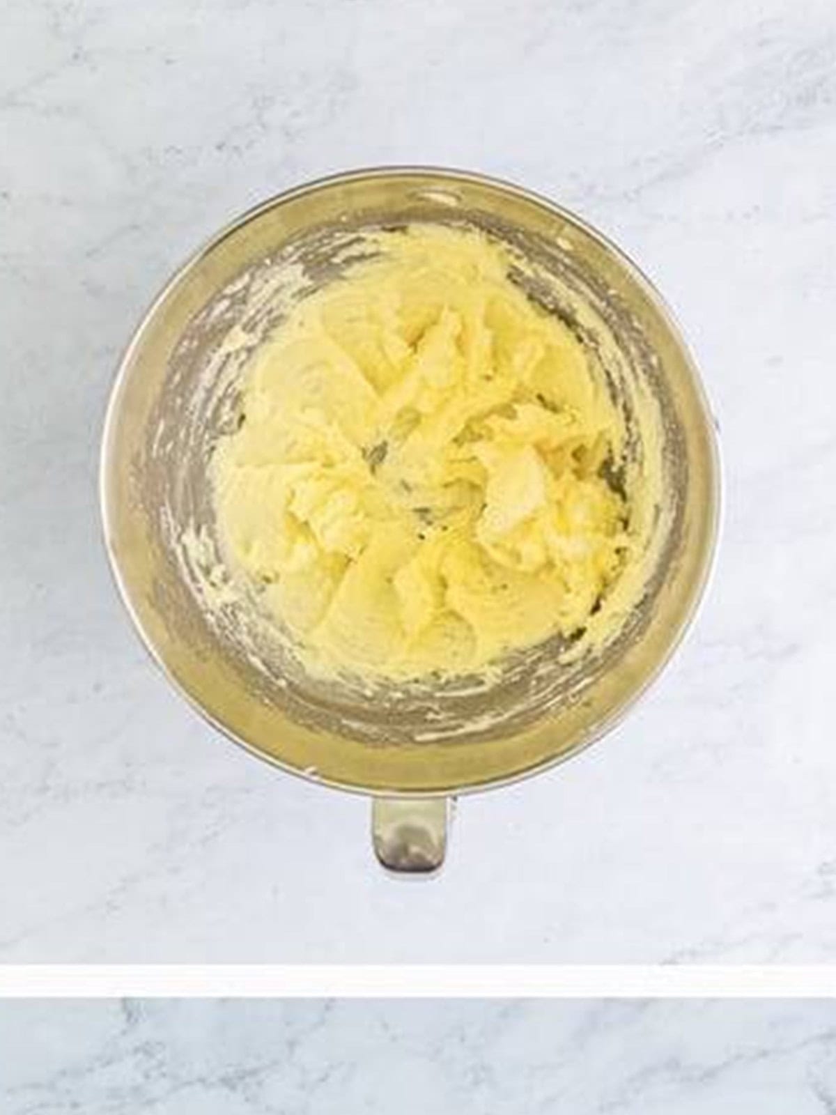 Creaming cold salted butter with powdered sugar and granulated sugar in a mixing bowl for Christmas shortbread cookies.