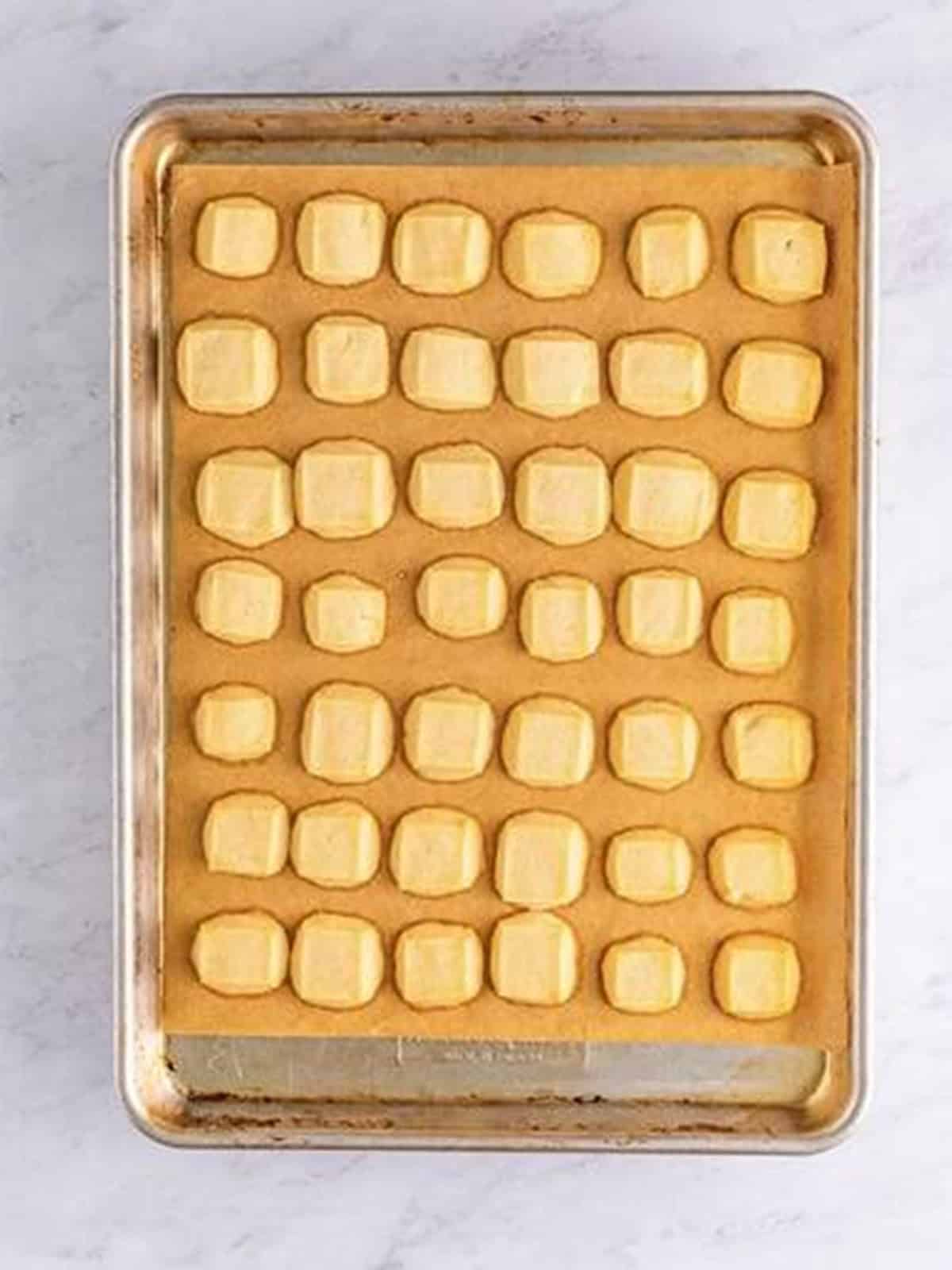 Baked shortbread cookie bites cooling on the sheet tray with lightly golden edges.