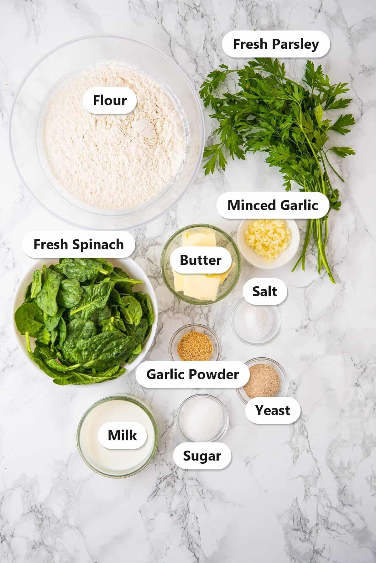 Labeled ingredients for Christmas Tree Pull Apart Bread including flour, fresh spinach, milk, butter, yeast, minced garlic, fresh parsley, garlic powder, sugar, and salt.