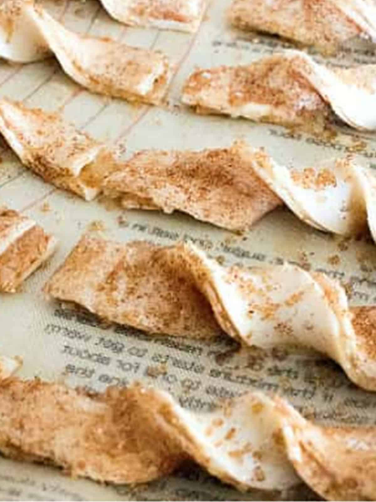Cinnamon apple twists twisted and arranged on a parchment lined baking sheet.