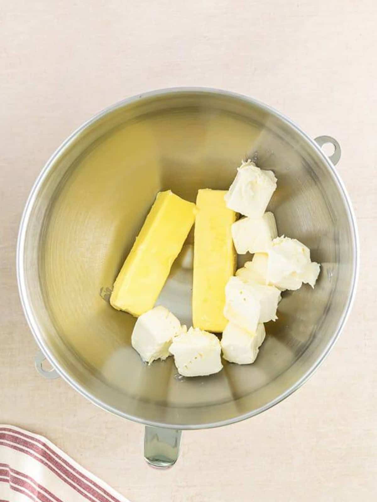 Cream cheese and butter in the bowl of a stand mixer ready to whip for Cinnamon Cream Cheese Frosting.
