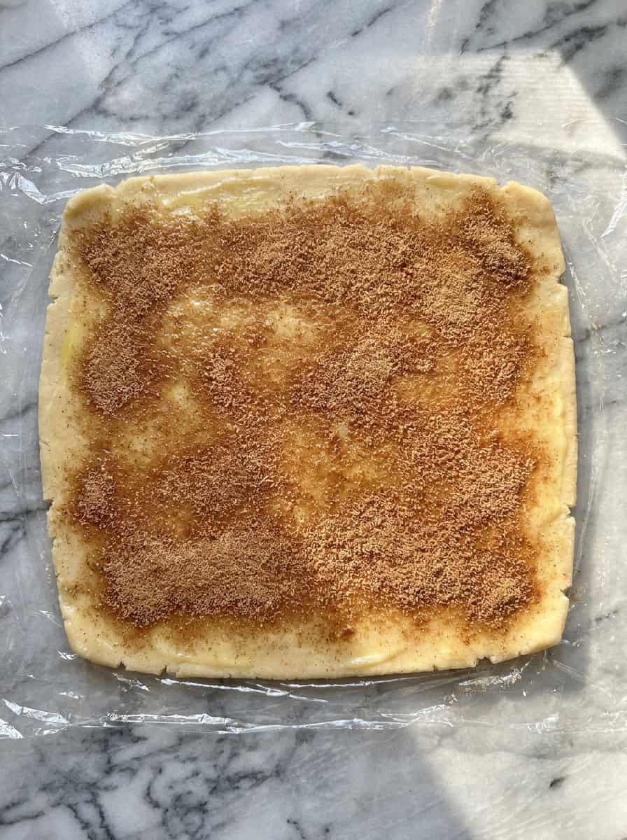 Rolled-out sugar cookie dough brushed with melted butter and sprinkled with cinnamon sugar.