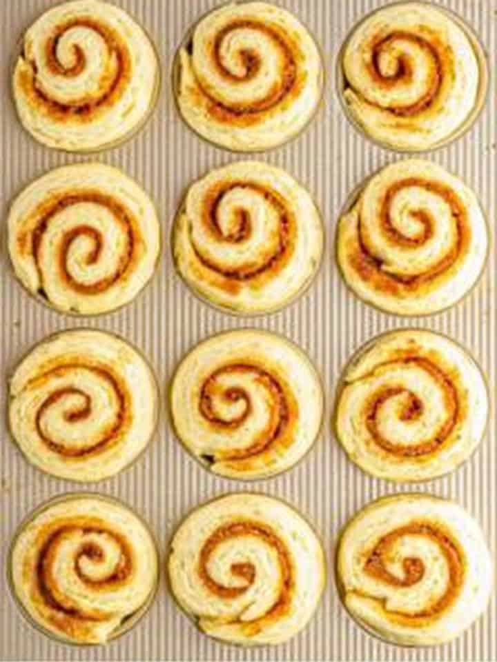Cinnamon Rolls rising in a lined muffin tin until doubled in size.
