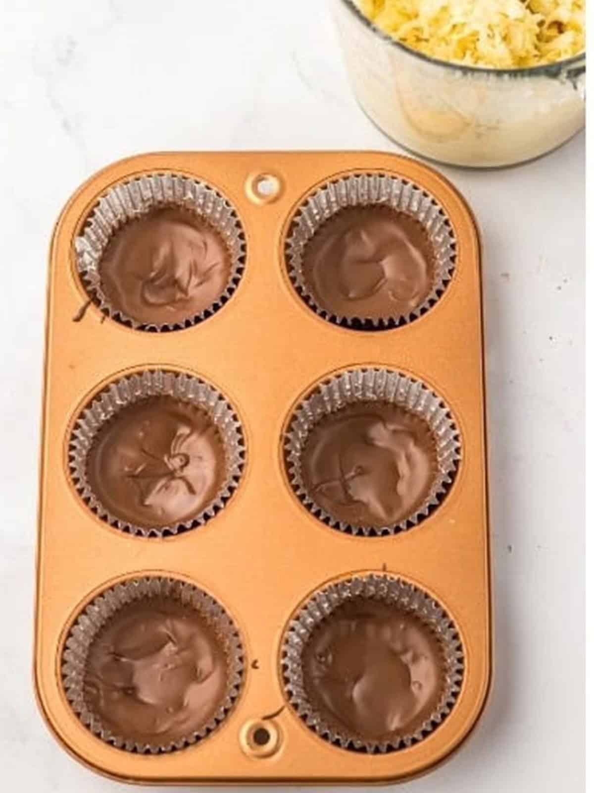 Melted chocolate almond bark spread into cupcake liners to form the Coconut Candy shells.