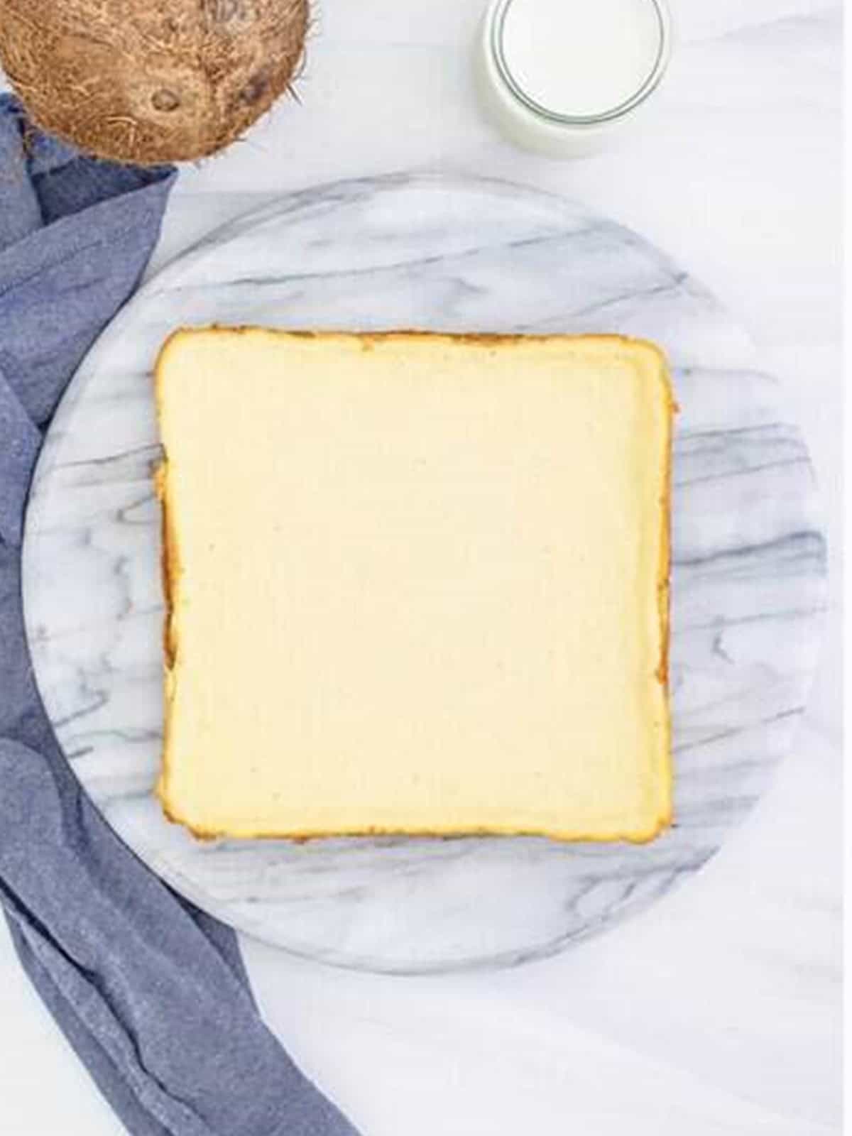 The baked coconut cheesecake cooling as a whole slab on the counter.
