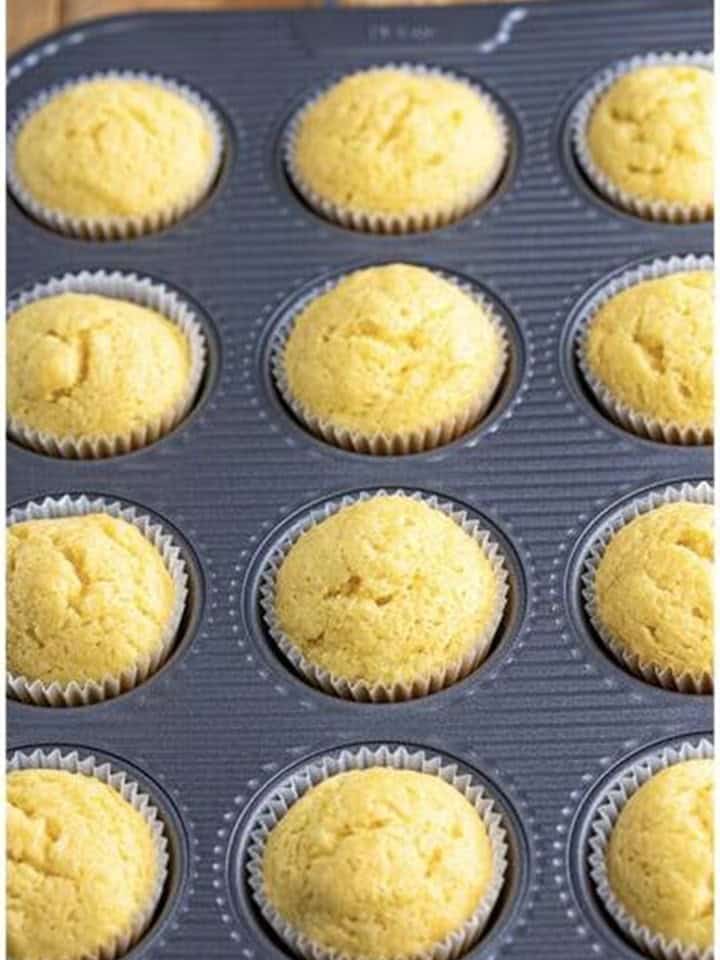 Golden baked Coconut Cupcakes in the muffin tin fresh from the oven.