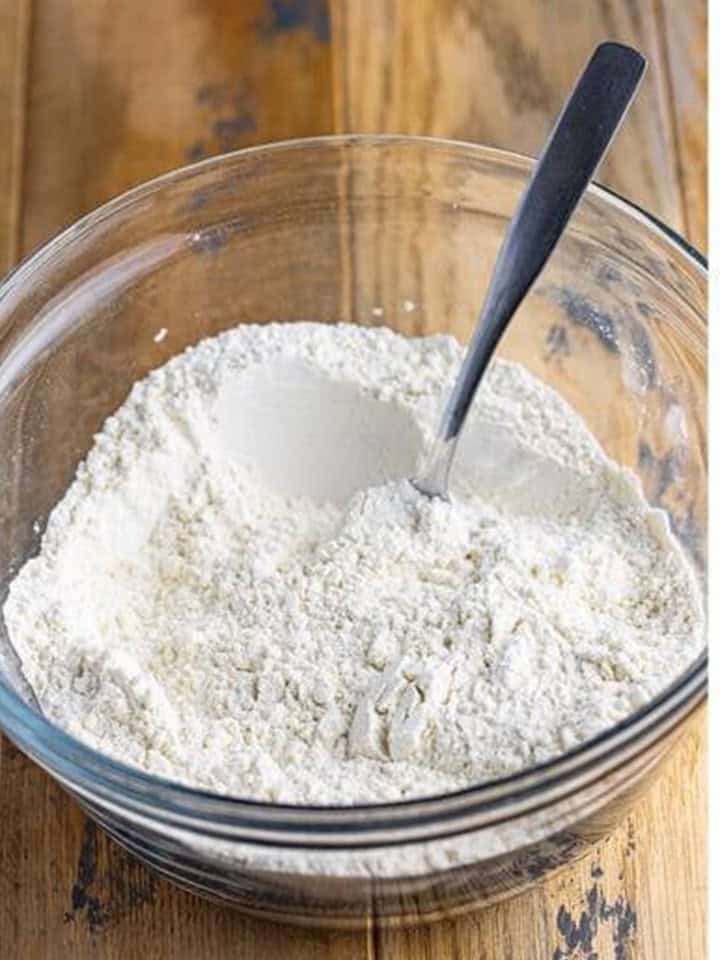 Flour, baking powder, and salt stirred together in a glass bowl for Coconut Cupcakes.