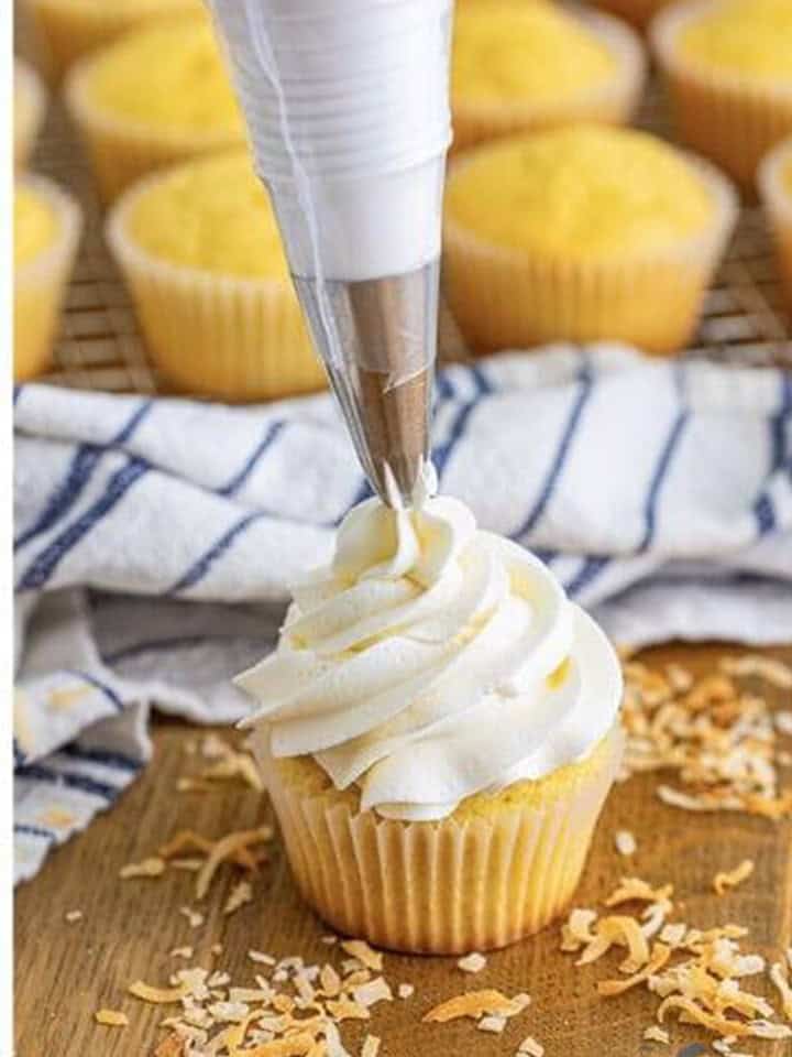 Fluffy coconut buttercream piped in a tall swirl onto a cupcake.