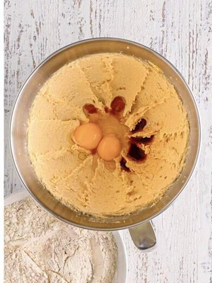 Eggs and vanilla added to creamed butter and brown sugar in a stand mixer bowl.