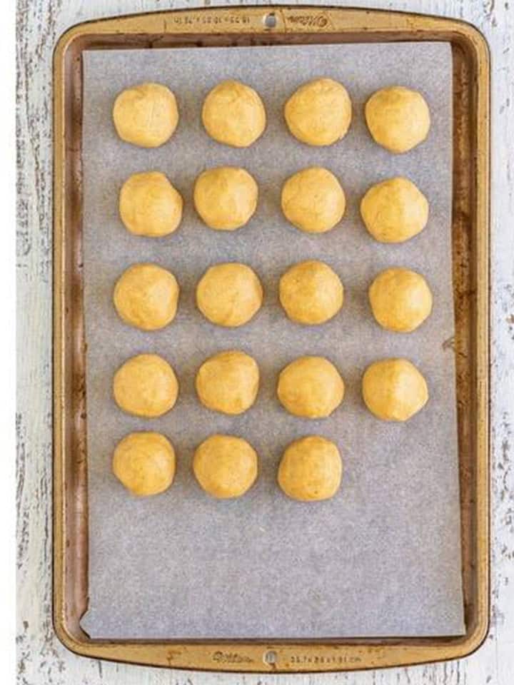 Coffee cake cookie dough balls on a parchment lined sheet tray ready to chill.