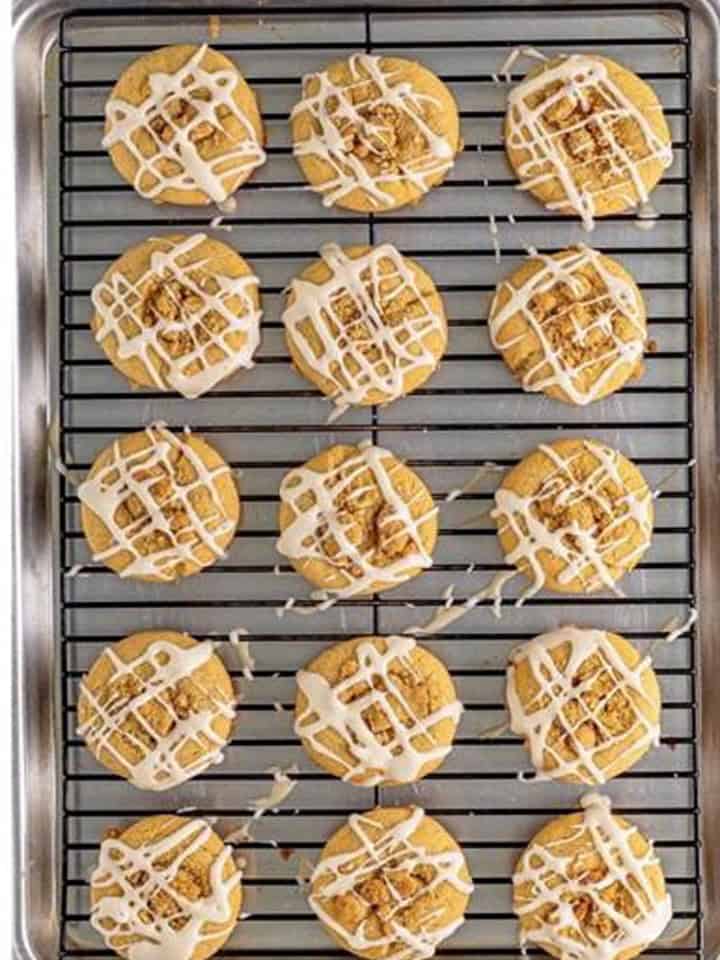 Baked coffee cake cookies drizzled with vanilla glaze on a cooling rack.