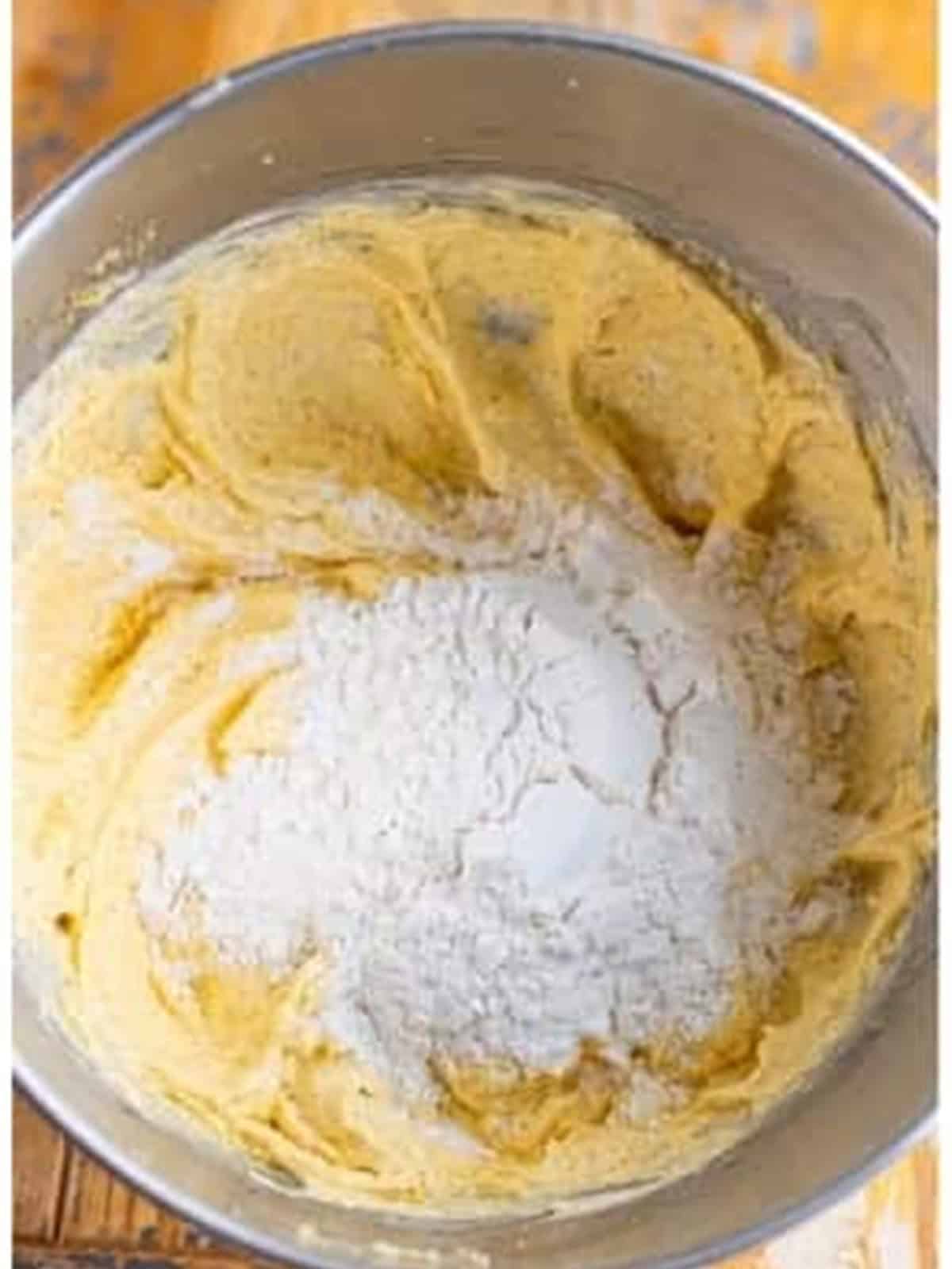 Self rising flour added to the coffee walnut cake batter in a mixing bowl.