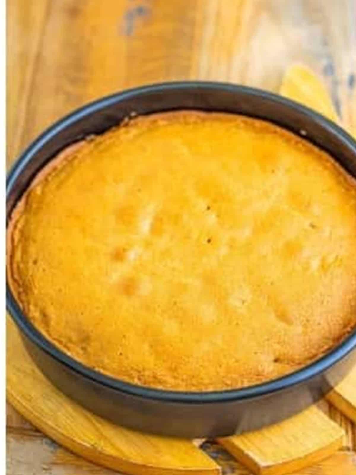 A baked coffee walnut sponge cake layer cooling in a round pan.