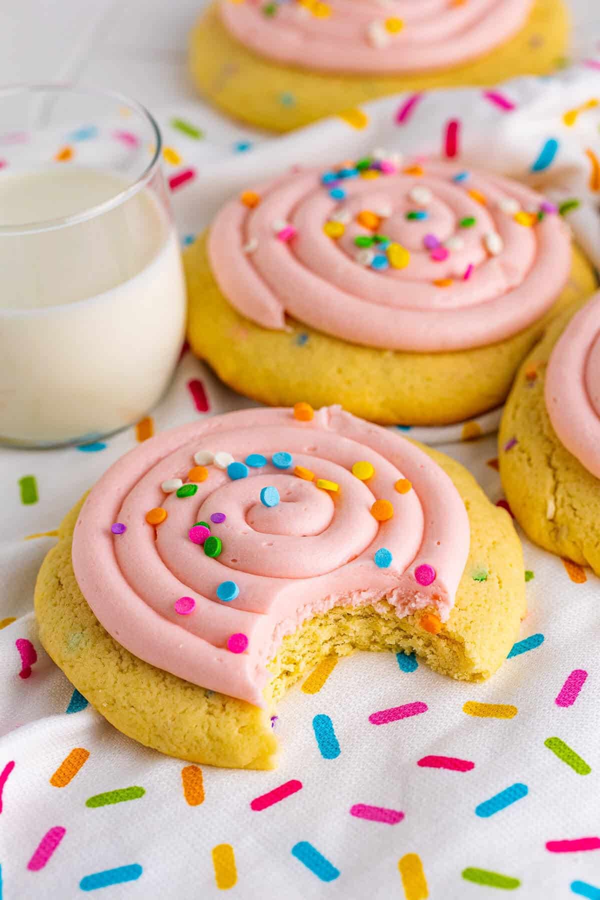 A confetti cake cookie with a bite taken out showing the soft, cakey, sprinkle-studded center.