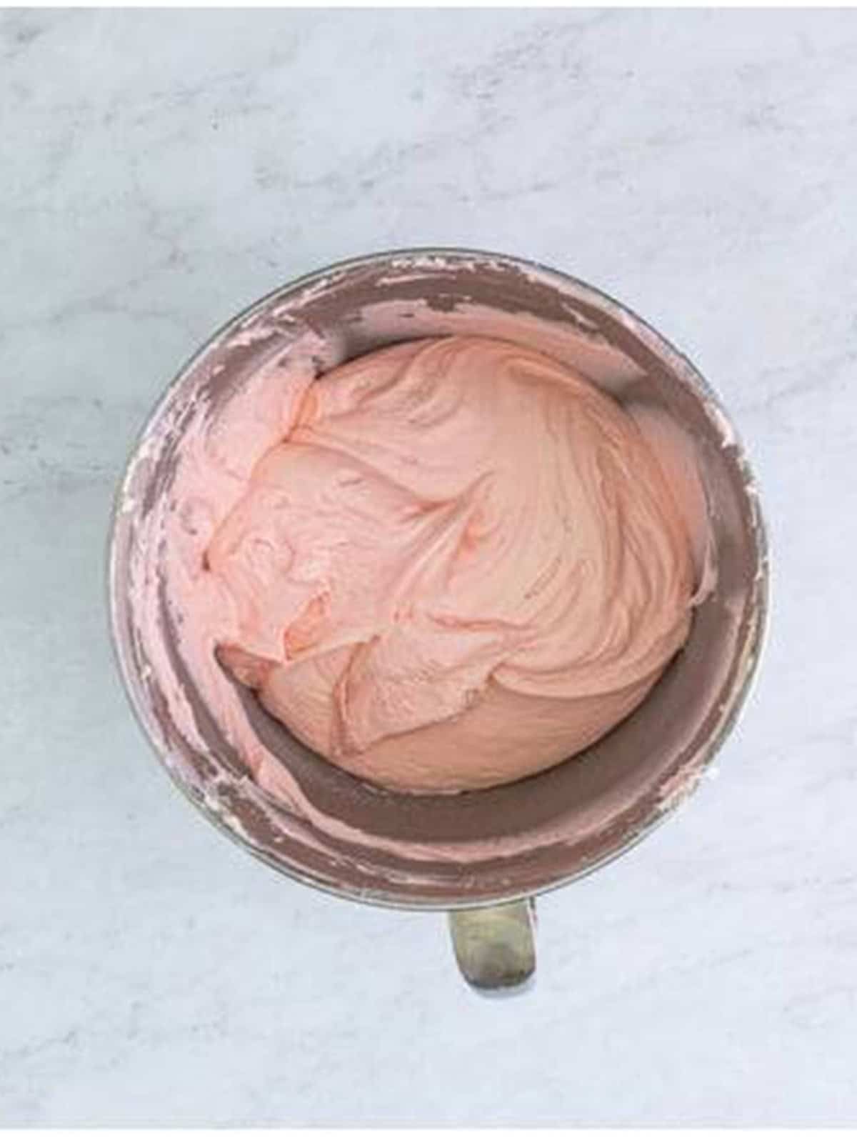 Pink cream cheese frosting whipped until light and fluffy in a mixing bowl.