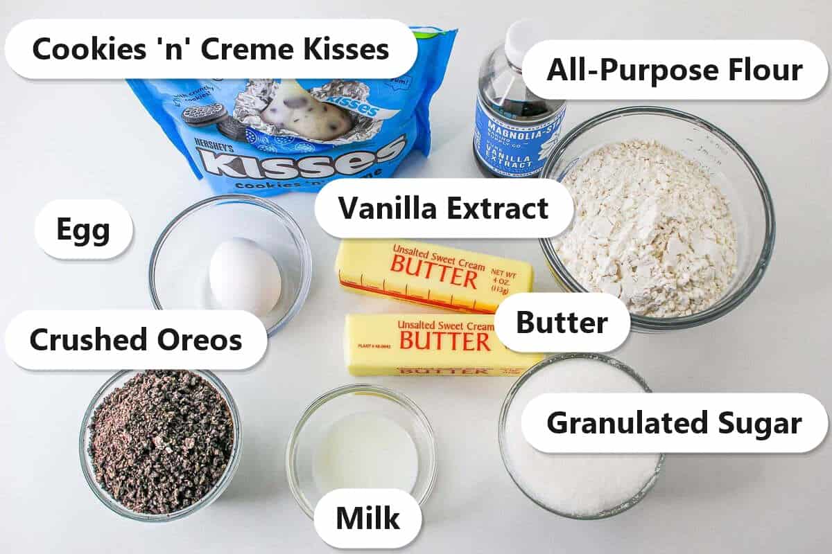 Labeled ingredients to make cookies and cream blossom cookies including cookies n creme Kisses, crushed Oreos, butter, sugar, flour, egg, milk, and vanilla extract.