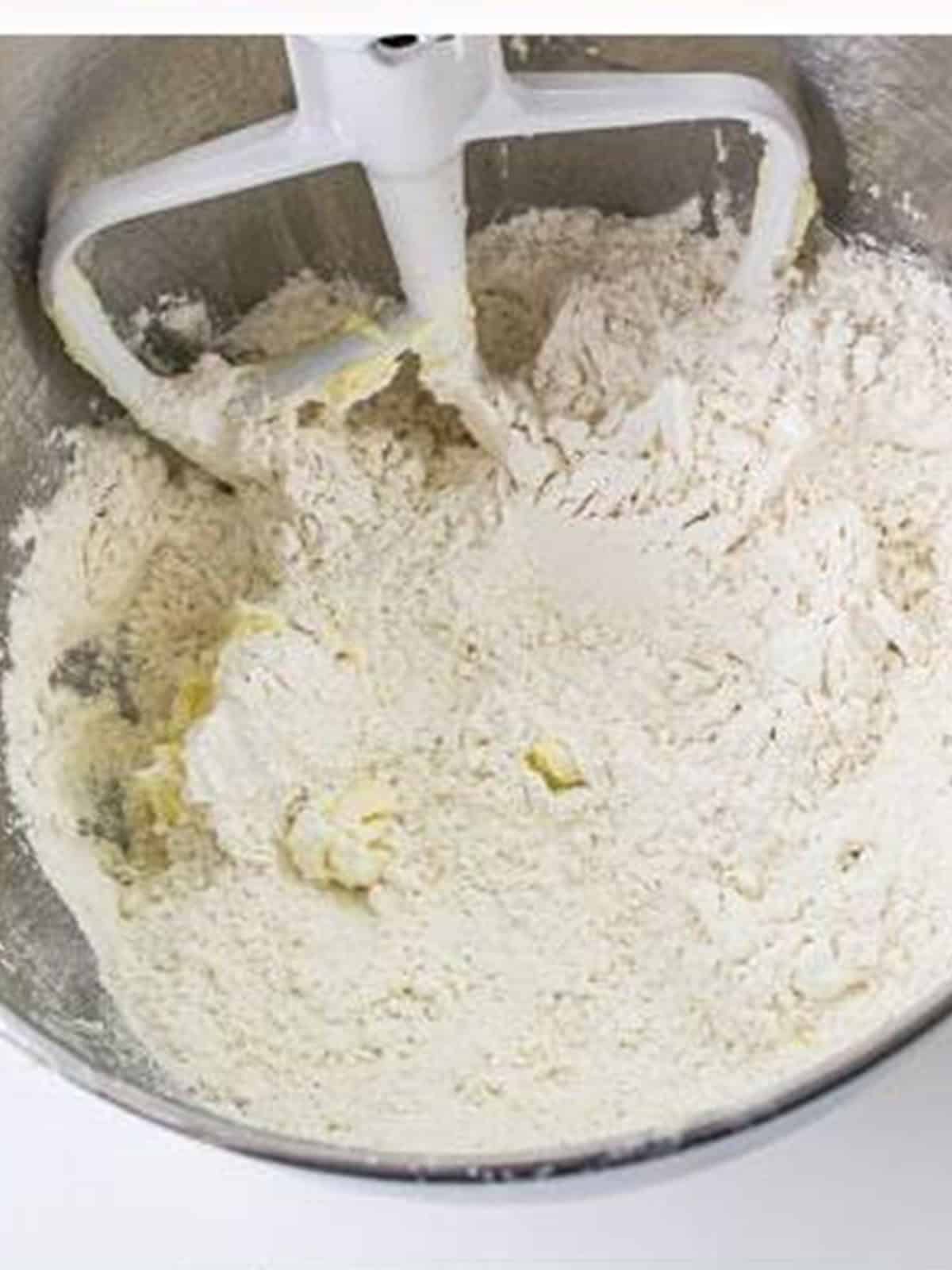 Flour mixture added to the wet ingredients in the mixer bowl for blossom cookies.
