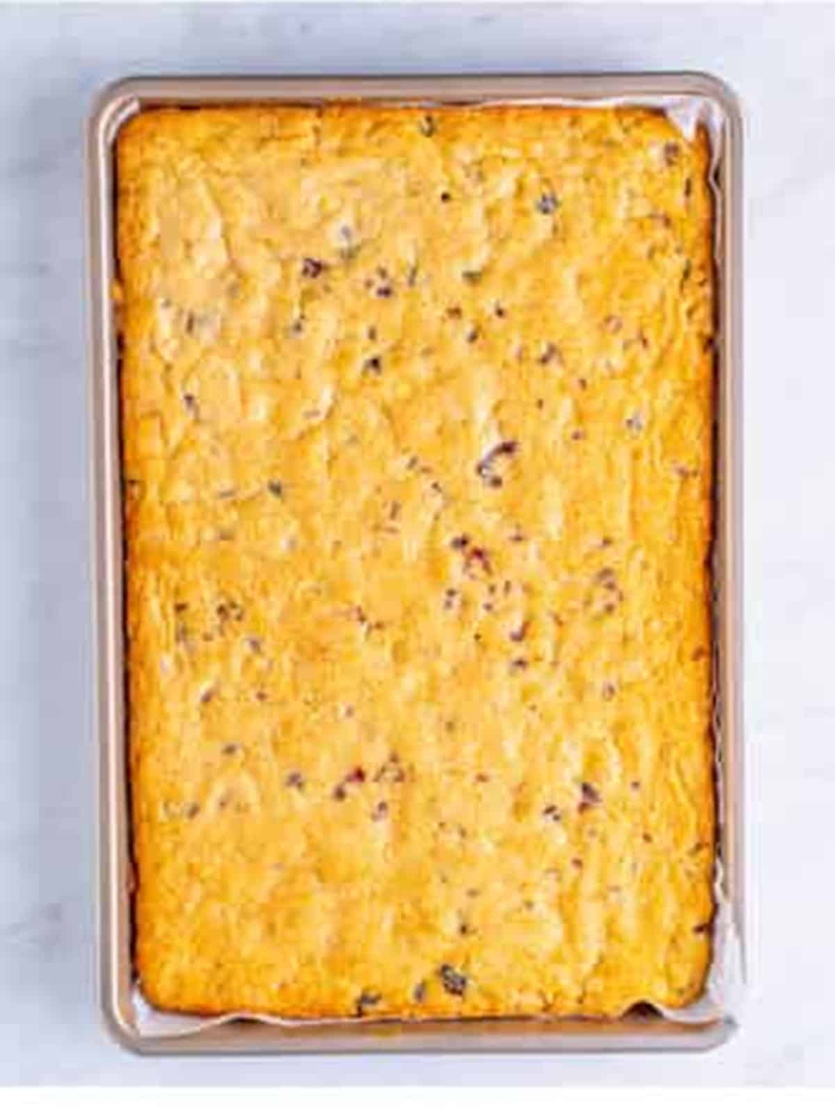 Baked cranberry blondie base golden brown in a sheet pan.