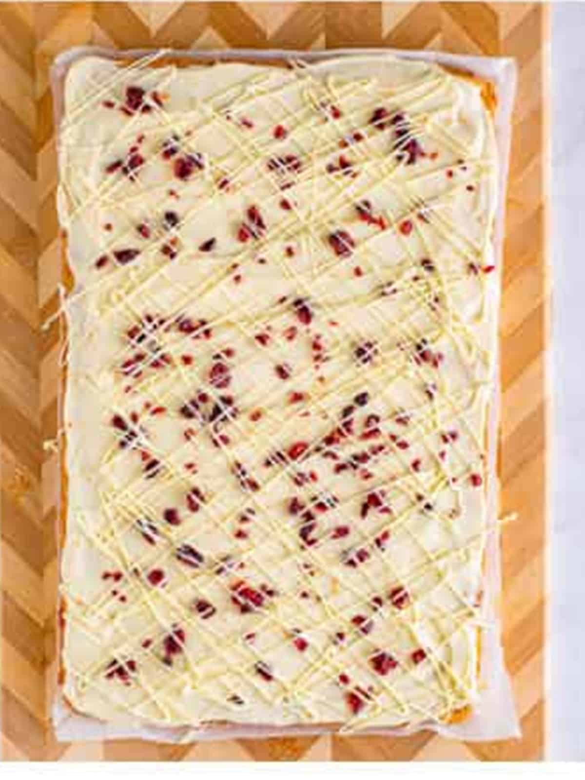 Frosted cranberry bliss bars topped with dried cranberries and white chocolate drizzle.