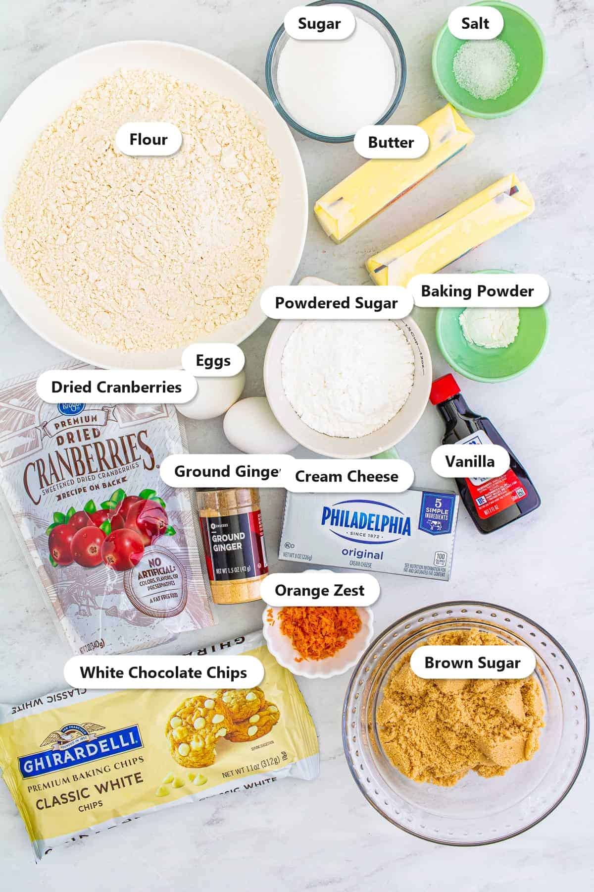 Labeled ingredients for cranberry bliss bars including flour, brown sugar, dried cranberries, white chocolate chips, cream cheese, and ginger.