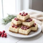 A stack of white chocolate Cranberry Cheesecake Bars topped with sugared cranberries.